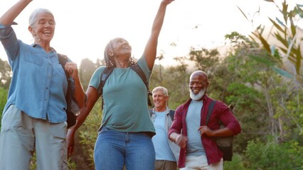 Wall Mural - Multi cultural group of senior friends enjoying hiking through countryside together - shot in slow motion