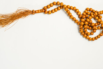 The Holy Al Quran with written arabic calligraphy meaning of Al Quran and rosary beads or tasbih on white background, isolated with copy space.