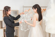 © buritora - 式場・ドレスショップでドレスを選ぶ新婦・花嫁とプランナーの女性
