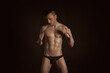 © vladorlov - Adult attractive man with a beautiful body posing in the studio. Black background.
