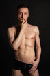 © vladorlov - Adult attractive man with a beautiful body posing in the studio. Black background.