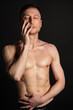 © vladorlov - Adult attractive man with a beautiful body posing in the studio. Black background.