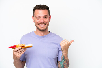 Wall Mural - Young caucasian man holding sashimi isolated on white background pointing to the side to present a product