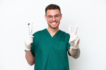 Wall Mural - Young caucasian dentist man isolated on white background smiling and showing victory sign