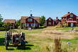 An old tractor, red houses and a communal hand water pump in a small village on the island of Harstena in the Gryt archipelago in the Baltic Sea