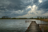 Fototapeta Na drzwi - Cloudy stormy sky over a lake with a pier