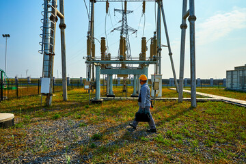 Asian worker inspecting high voltage power station