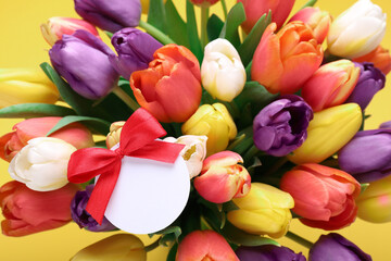  Bouquet of beautiful colorful tulips with blank card on yellow background, closeup. Birthday celebration