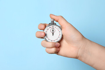 Wall Mural - Woman holding vintage timer on light blue background, closeup. Space for text