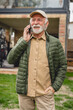 © Miljan Živković - One senior man stand in front of tiny house in day use smart phone