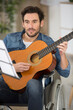 © auremar - young man playing guitar at home