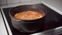 Traditional Finnish meat soup boiling in a pot on the electric stove 