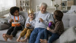 © fizkes - Happy grandson kid and multiethnic friends playing with positive grandpa, using musical toys, crown for role games, resting on sofa, talking, laughing, enjoying leisure, playtime, daycare activities