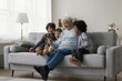 © fizkes - Cheerful happy senior grandfather and multiethnic little grandkids using smartphone for communication together, sitting close, laughing, having fun, resting on sofa, enjoying friendship, leisure