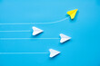 © JeromeMaurice - Top view of paper airplane - Yellow paper airplane origami flying to a different direction leaving other white airplanes on blue background
