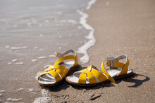 Yellow Sandals For Woman On Sand Beach At Ocean Coast. Holiday And Travel Concept