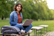© Prostock-studio - Beautiful Smiling Arab Female Student Using Laptop While Relaxing On Bench Outdoors