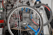 In Bicycle Repair Shop, Wheels Undergo Thorough Maintenance And Stretching Spokes. On Blue Racks There Wheels From Bicycles For Servicing And Stretching The Spokes. Maintenance And Repair Of Bicycles