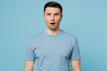 Wall Mural - Young sad shocked surprised scared caucasian european man wearing casual t-shirt look camera with opened mouth isolated on plain pastel light blue cyan background studio portrait. Lifestyle concept.