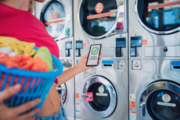 Young woman pays for laundry service using phone and banking application