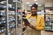 © Seventyfour - Waist up portrait of smiling black woman enjoying work in supermarket and looking at camera