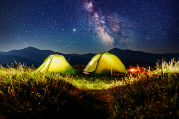 Wall Mural - epic starry sky above illuminated tents in the mountains. carpathian mountains, ukraine, europe.