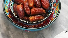 Dried Dates On Concrete. Bowl Of Pitted Dates On A Gray Background. Ramadan Kareem Fasting Month Concept. Tilt Up Camera Movement