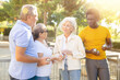 © JackF - A group of multiracial middle aged mixed-sex adult people standing next to each other and talking during a break in petanque game outside