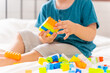 © CandyRetriever  - Adorable caucasian baby boy sitting on the bed and playing colorful  plastic block in bedroom. Little child boy kid enjoy and fun playing education and learning toy game without digital device gadget