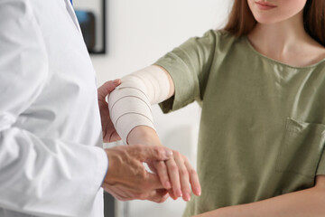 Sticker - Orthopedist applying bandage onto patient's elbow in clinic, closeup