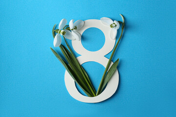 Wall Mural - Beautiful snowdrops and paper number 8 on light blue background, flat lay