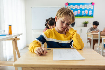 Caucasian young boy student doing an exam test at elementary school. 