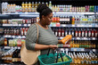 © Seventyfour - Side view portrait of smiling black woman grocery shopping in supermarket
