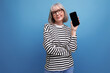 © Ivan Traimak - middle-aged youth 60s woman holding a smartphone with a mockup on a bright background with copy space