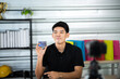 © chokniti - Young seller man look intend holding looking at camera to present product via live online for shopping online with e-commerce sell, Asian blogger showing goods in front of camera recording vlog video