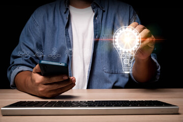 Fototapete - hand of a man with a light bulb And there is a gear icon in it And he is using smartphone and computer. The idea of inspiration from online technology. innovation idea concept