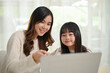 © bongkarn - Kind and caring Asian sister helping her little sister with online study class on laptop