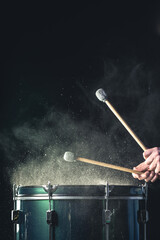 Wall Mural - A man plays a musical percussion instrument with sticks on a dark background.