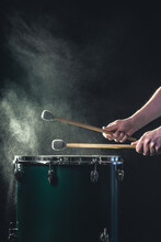 A Man Plays A Musical Percussion Instrument With Sticks On A Dark Background.