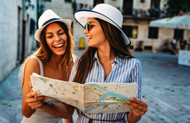 Wall Mural - Happy group of young women friends enjoying sightseeing tour in the city on summer vacation.