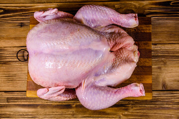 Wall Mural - Wooden cutting board with the whole uncooked chicken. Top view