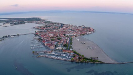 Wall Mural - 4k drone flight moving to the side footage (Ultra High Definition) of public beach of Grado port, small town located between Venice and Trieste. Magnificent evening seascape of Adriatic sea.