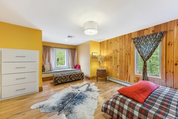 Sticker - Interior shot of a wooden bedroom with a white ceiling and a decorative carpet.