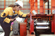 © Nassorn - Latin woman engineer inspecting heavy machinery system in production line for manufacturing safety. Female technician doing repair service. Maintenance machine equipment in metalwork factory concept.