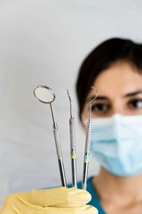 Canvas Print - Hispanic woman dentist holding a dental instruments