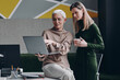 © gstockstudio - Two confident women using technologies and communicating while working in office together