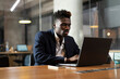 © JustLife - Portrait of successful businessman in office. Young smiling man using the laptop..