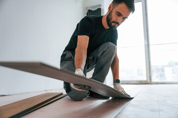 Wall Mural - Fitting the planks. Man is installing new laminated wooden floor