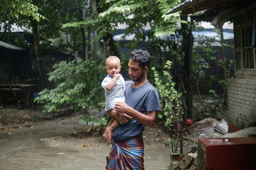 Wall Mural - South asian young rural father holding his little son, village baby boy playing with his young dad, lovely family moments in outdoor 