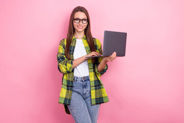 Wall Mural - Portrait of optimistic friendly girl with straight hairdo wear plaid shirt hold laptop writing email isolated on pink color background